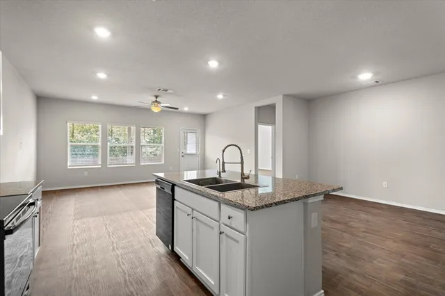 a kitchen with granite countertop white cabinets and wooden floor