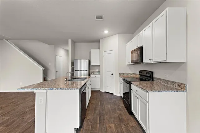 a kitchen with granite countertop a sink stove and refrigerator