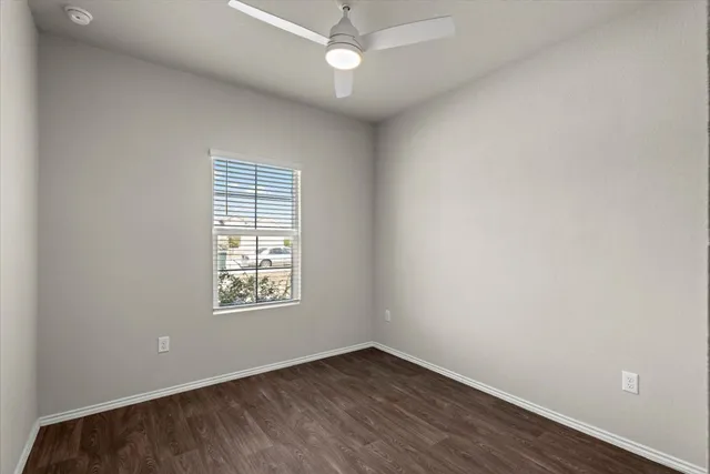 an empty room with wooden floor ceiling fan and windows