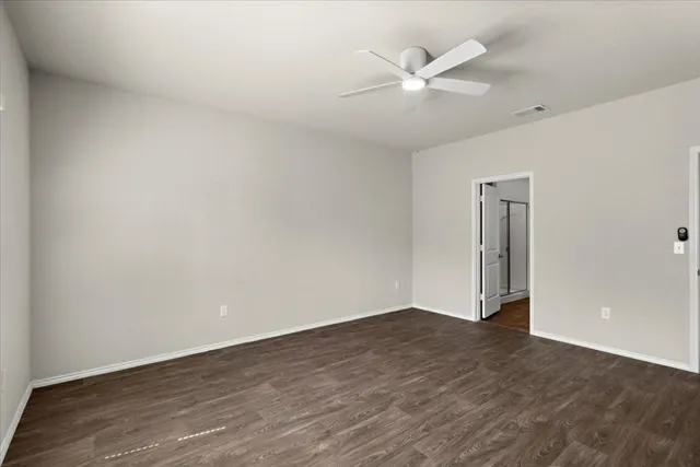 an empty room with wooden floor and ceiling fan