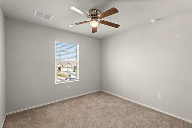 an empty room with a window and a fan