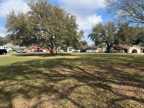 a view of a field with trees and houses in the background