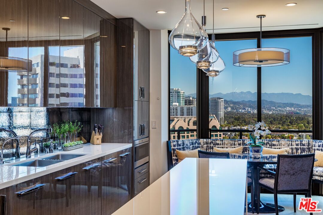 10601 Wilshire Boulevard, Unit 19E Los Angeles, CA 90024 - Photo 15 of 38 a view of a kitchen with kitchen island granite countertop a table chairs sink and window