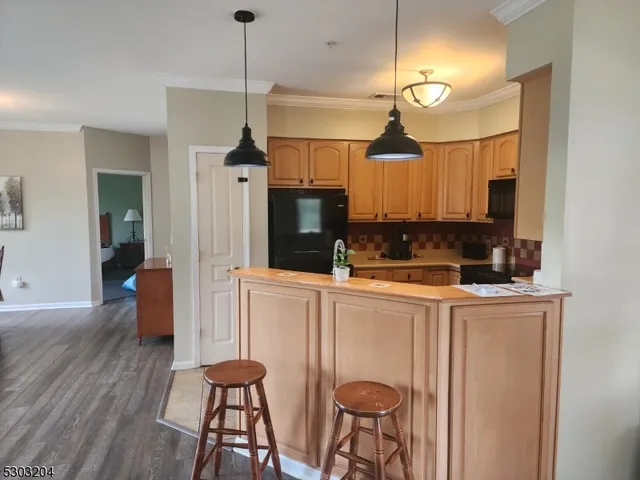 a kitchen with stainless steel appliances granite countertop a refrigerator a stove a sink dishwasher and a dining table with wooden floor