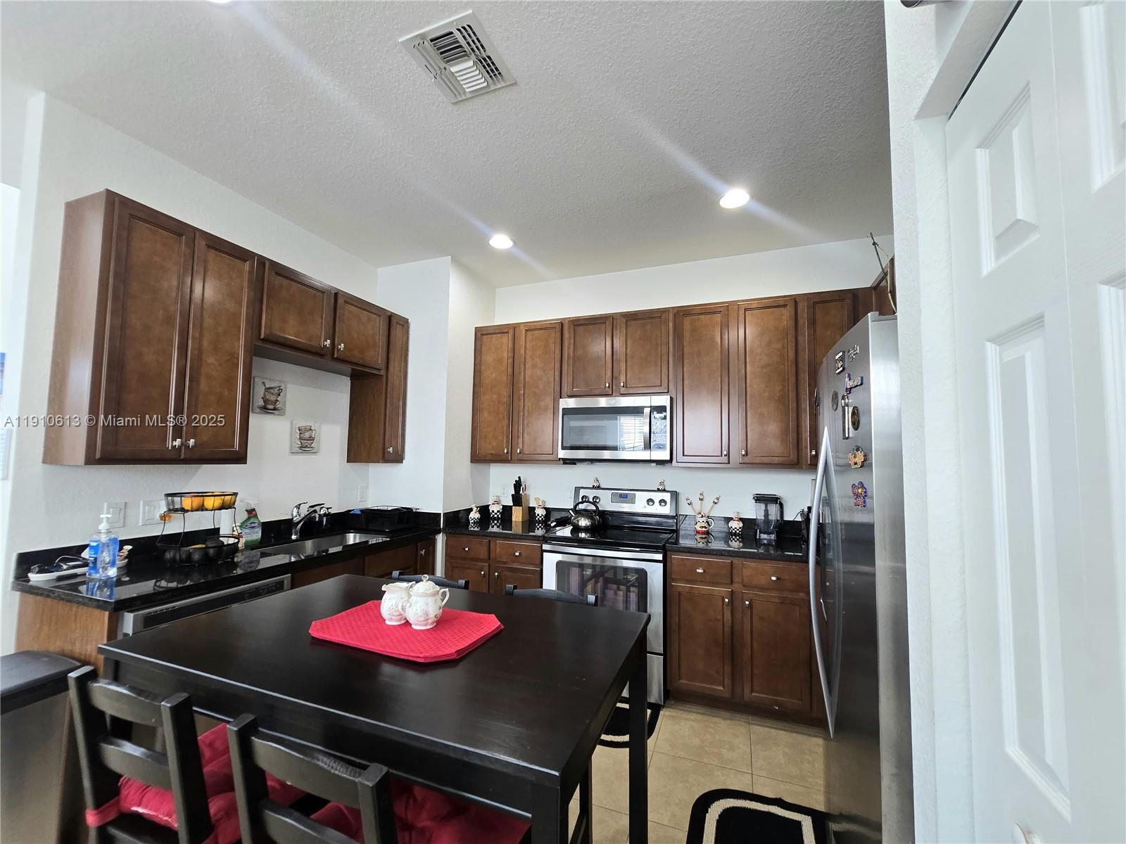 11938 Southwest 26th Court Miramar, FL 33025 - Photo 18 of 62 a kitchen with a dining table cabinets and appliances