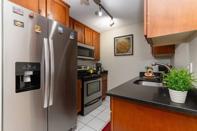 a kitchen with stainless steel appliances a refrigerator a sink a stove top oven a counter top space and cabinets