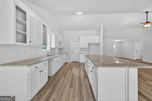 a large kitchen with granite countertop a sink and dishwasher a stove with wooden floors