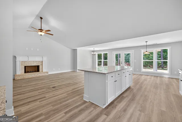 a kitchen with granite countertop a stove a sink and white cabinets with wooden floor