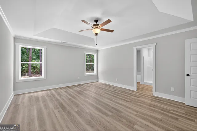 a view of an empty room with wooden floor and a ceiling fan