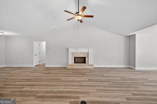 a view of an empty room with a fireplace and a chandelier fan