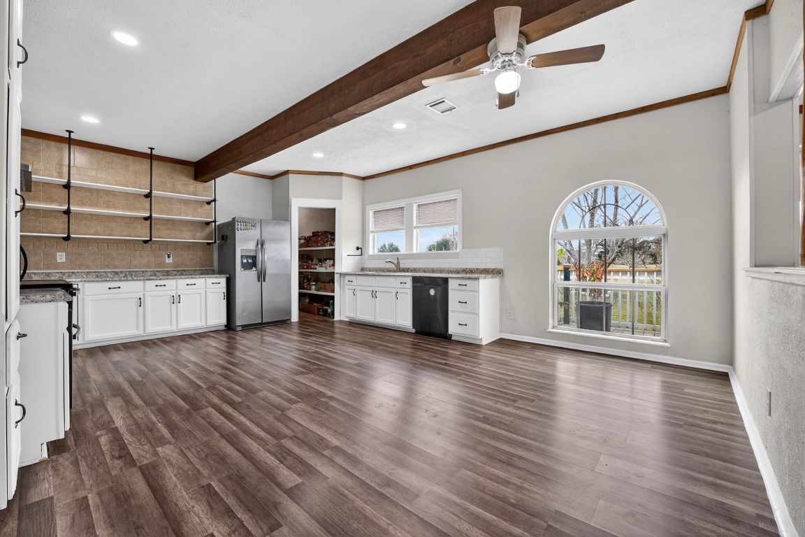 174 Monroe Lane Elgin, TX 78621 - Photo 11 of 21 an empty room with wooden floor a kitchen view and a large window
