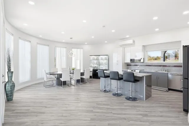 a kitchen with stainless steel appliances granite countertop a refrigerator a stove a dining table and chairs with wooden floor