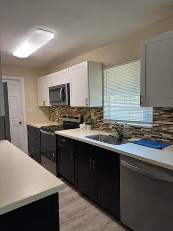 a kitchen with stainless steel appliances a sink a stove a microwave a center island and cabinets