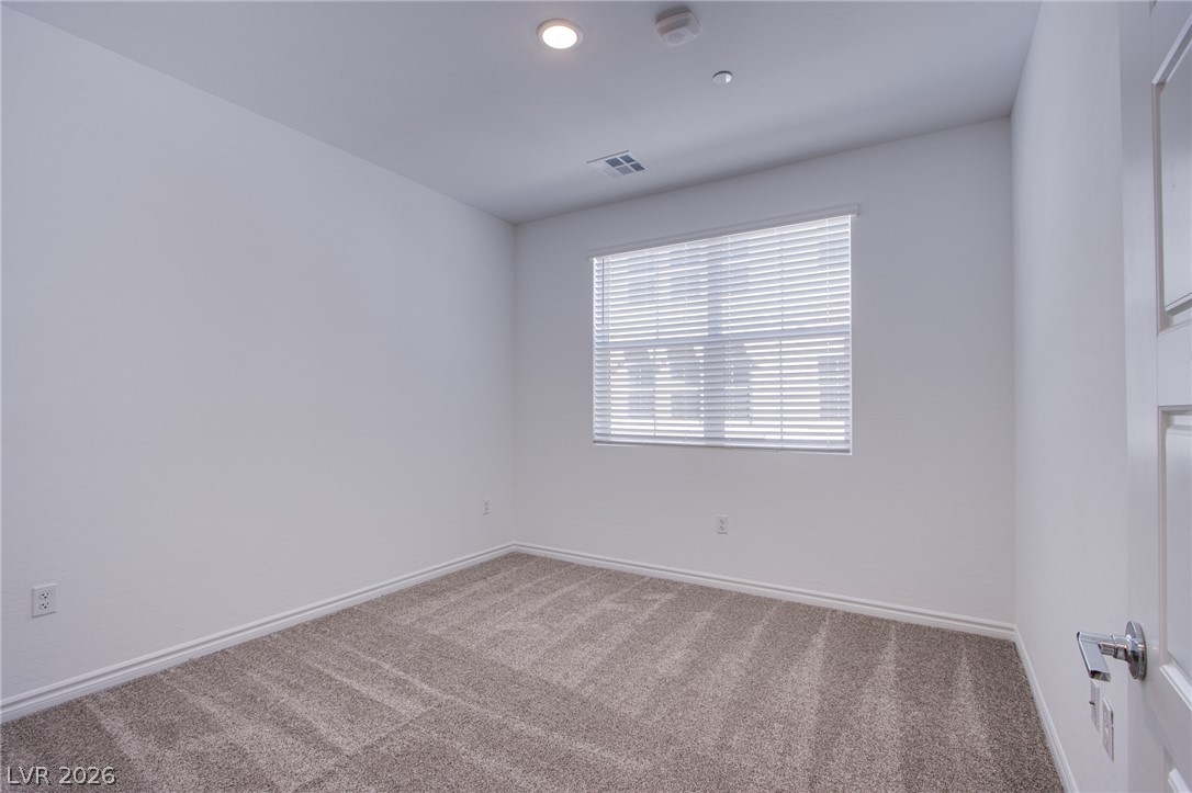 2555 Hampton Road, Unit 8201 Henderson, NV 89052 - Photo 24 of 33 Soft carpeting pairs with a bright window inside this versatile secondary bedroom space.