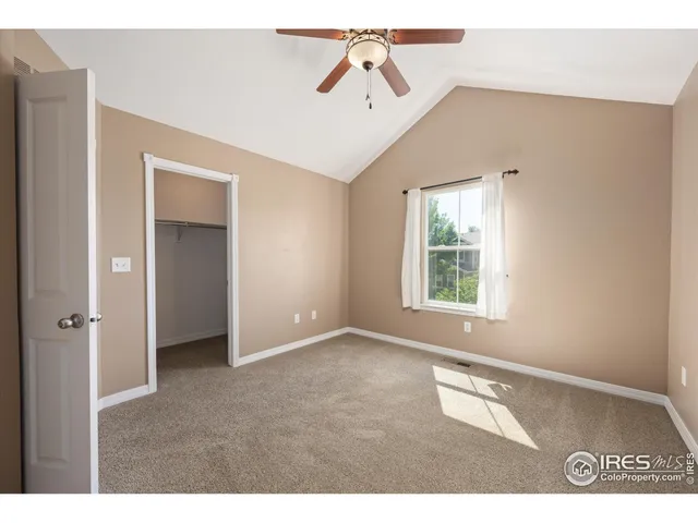 a view of an empty room with window and a ceiling fan