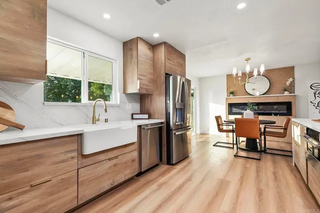 a kitchen with stainless steel appliances a stove a sink dishwasher a refrigerator and a dining table with wooden floor