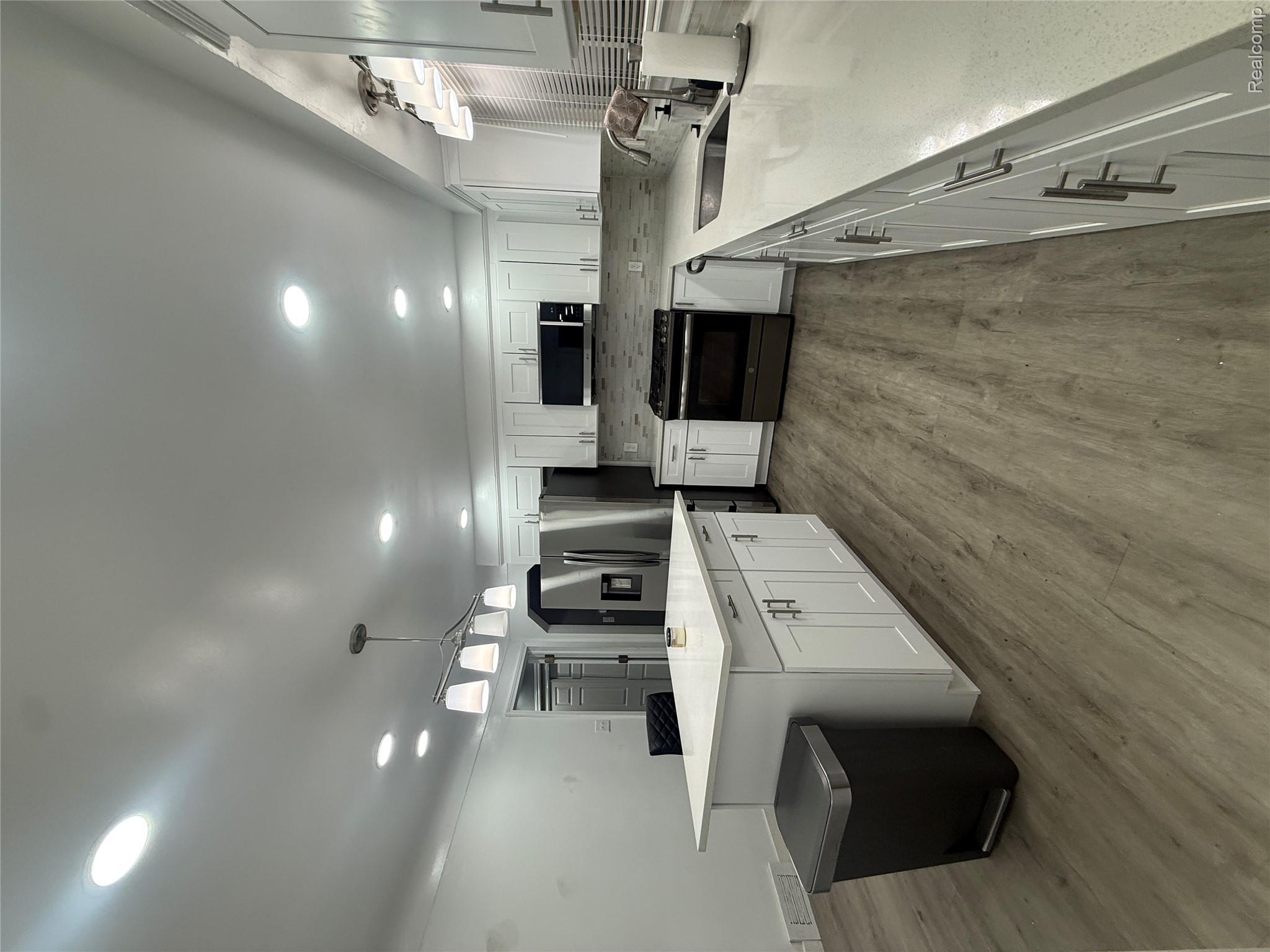 44862 Willis Road Belleville, MI 48111 - Photo 4 of 14 Kitchen featuring hanging light fixtures, dark wood-type flooring, backsplash, stainless steel appliances, and white cabinets