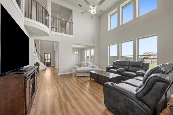 a view of a living room and kitchen with furniture wooden floor windows and a chandelier