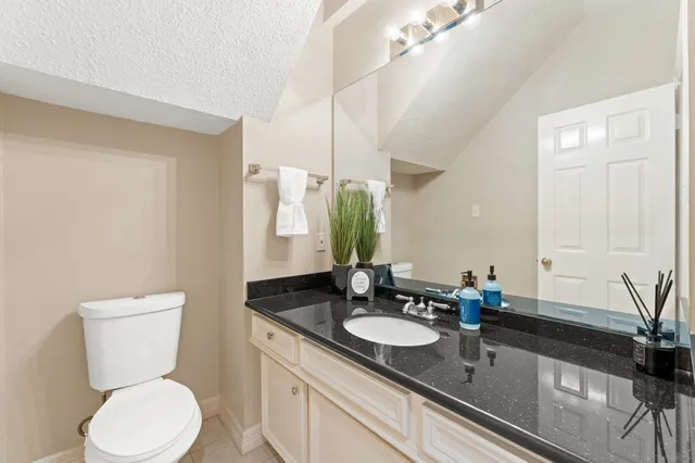 a bathroom with a granite countertop sink toilet and mirror