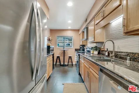 a kitchen with stainless steel appliances granite countertop sink stove refrigerator and cabinets