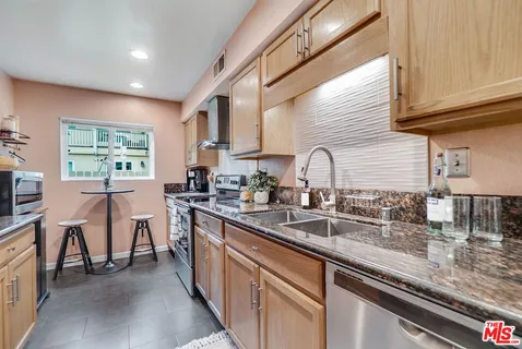 a kitchen with stainless steel appliances granite countertop a sink a stove and a wooden floors