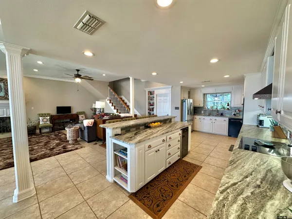 a large white kitchen with stainless steel appliances kitchen island granite countertop a large counter top and cabinets