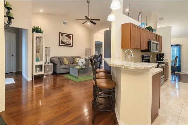 a kitchen with stainless steel appliances kitchen island granite countertop a refrigerator a stove and a sink with granite countertops