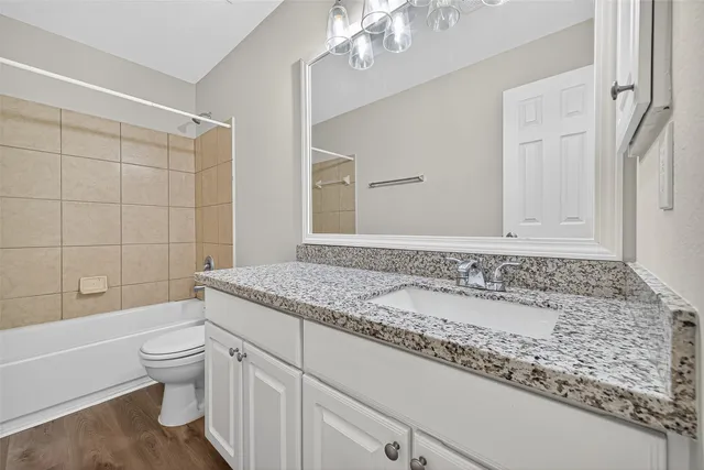a bathroom with a granite countertop sink a toilet and bathtub