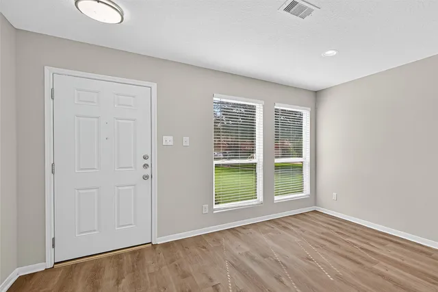 an empty room with wooden floor and windows