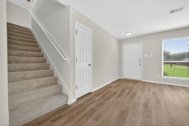 a view of an empty room with wooden floor and a window