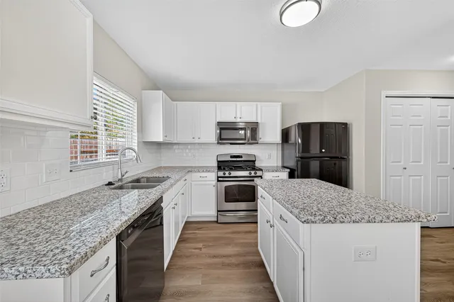 a kitchen with kitchen island granite countertop a sink stove refrigerator and microwave