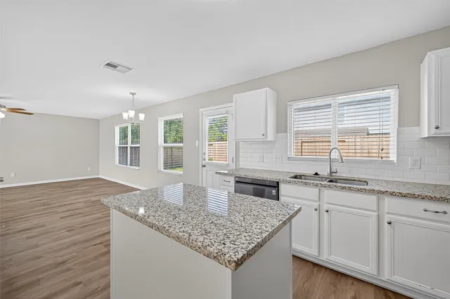 a kitchen with granite countertop a sink and white cabinets