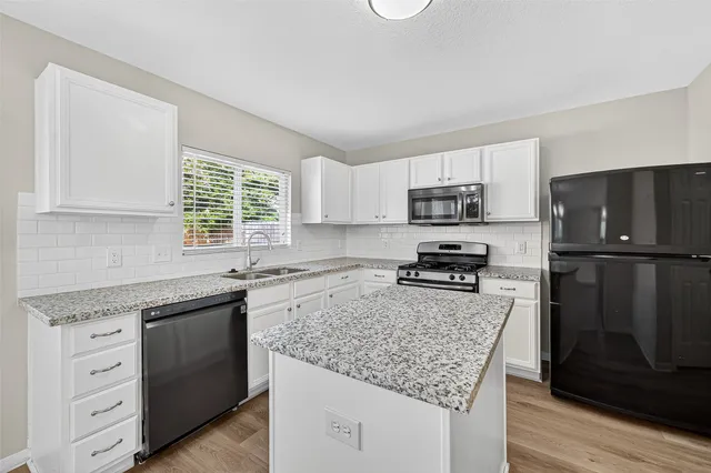 a kitchen with granite countertop a refrigerator stove and sink
