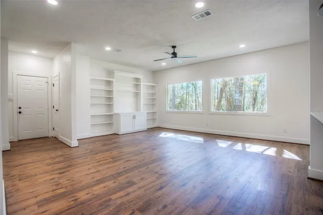 a view of an empty room with wooden floor and a window