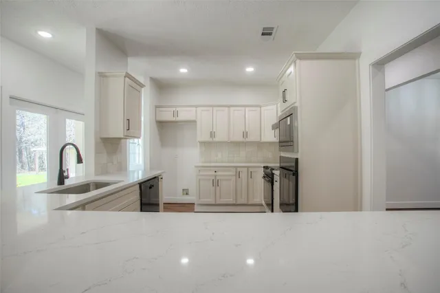 a kitchen with stainless steel appliances granite countertop a sink a stove and a refrigerator