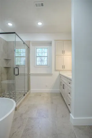 a spacious bathroom with a tub sink shower and mirror