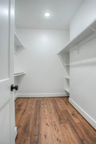 a view of an empty room with wooden floor and closet
