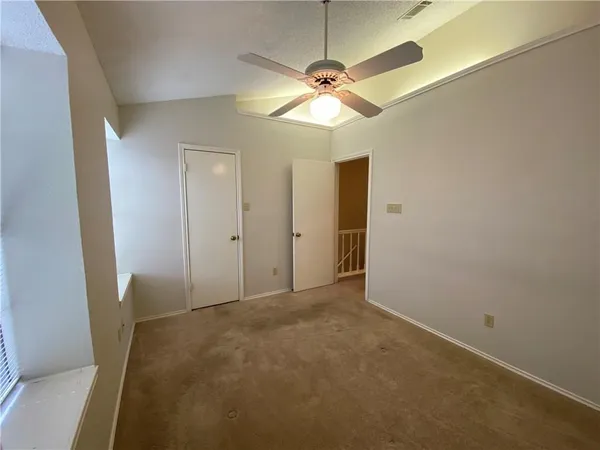 an empty room with a chandelier fan and a bathroom