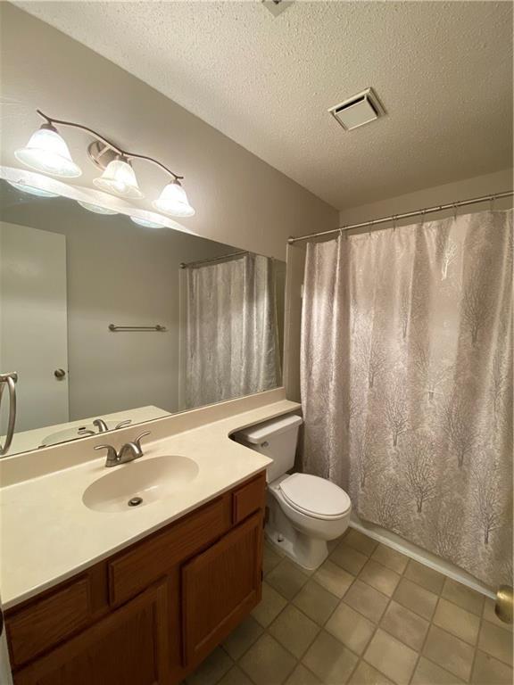 12325 Los Indios Trail, Unit 9 Austin, TX 78729 - Photo 19 of 30 Bathroom with a shower with shower curtain, vanity, a textured ceiling, and light tile patterned floors