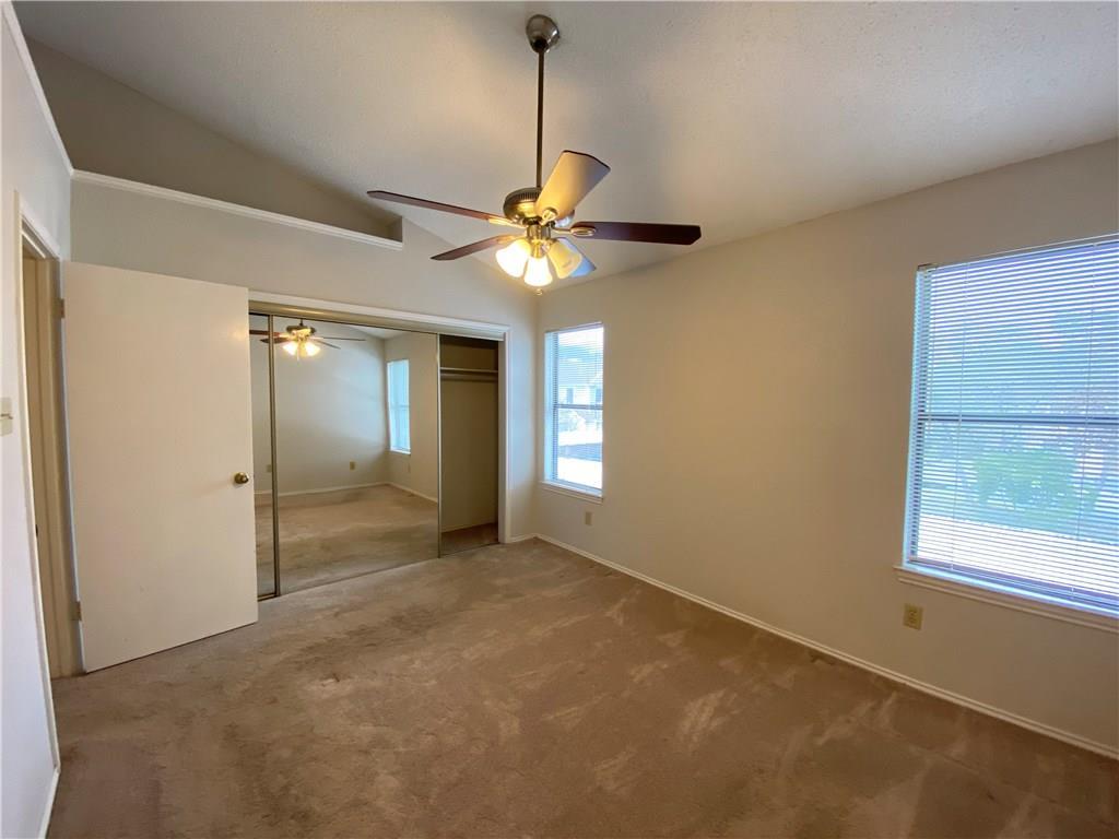 12325 Los Indios Trail, Unit 9 Austin, TX 78729 - Photo 21 of 30 Unfurnished bedroom with vaulted ceiling, carpet flooring, a closet, and a ceiling fan