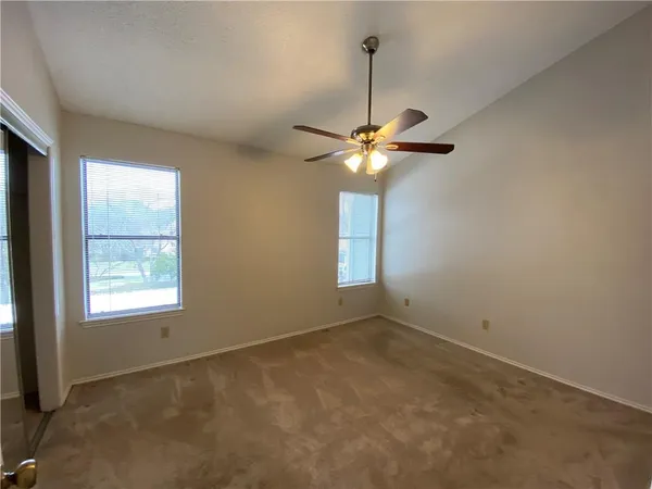 a view of an empty room with a chandelier fan and a window