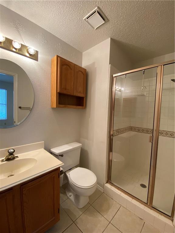 12325 Los Indios Trail, Unit 9 Austin, TX 78729 - Photo 24 of 30 Bathroom with vanity, a stall shower, light tile patterned flooring, and a textured ceiling