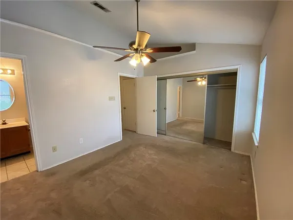 an empty room with closet and a chandelier fan