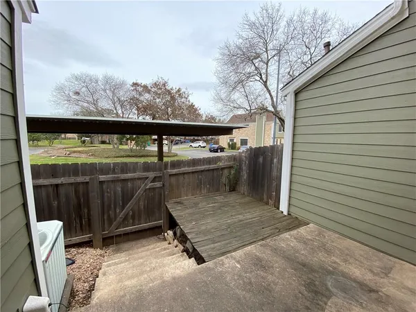 a view of a patio with table and chairs and wooden fence