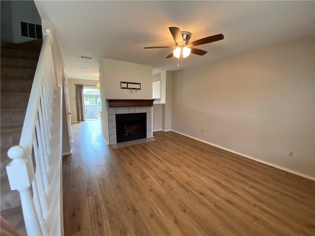 12325 Los Indios Trail, Unit 9 Austin, TX 78729 - Photo 5 of 30 Unfurnished living room featuring stairway, wood finished floors, a tile fireplace, and ceiling fan