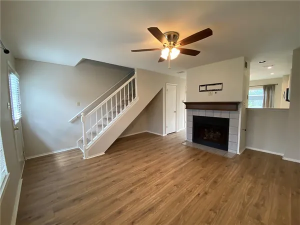 a view of a livingroom with wooden floor a ceiling fan and staircase