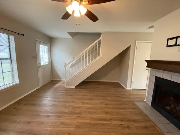a view of an empty room with wooden floor fireplace and a window