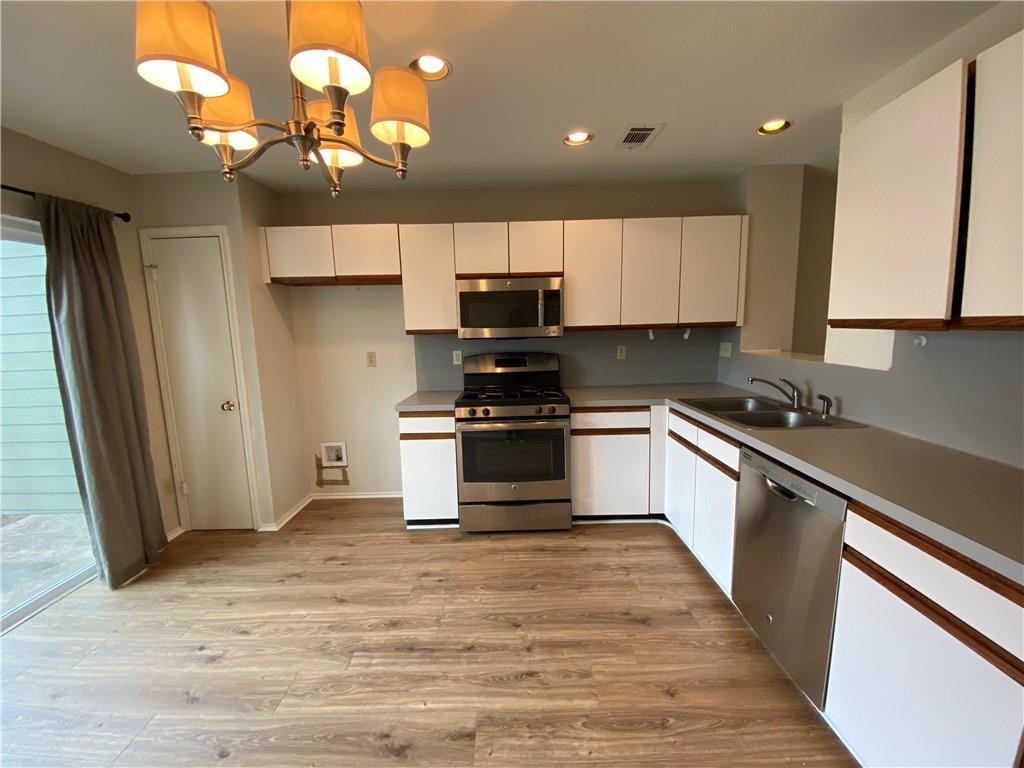 12325 Los Indios Trail, Unit 9 Austin, TX 78729 - Photo 10 of 30 Kitchen featuring white cabinets, stainless steel appliances, decorative light fixtures, recessed lighting, and light countertops
