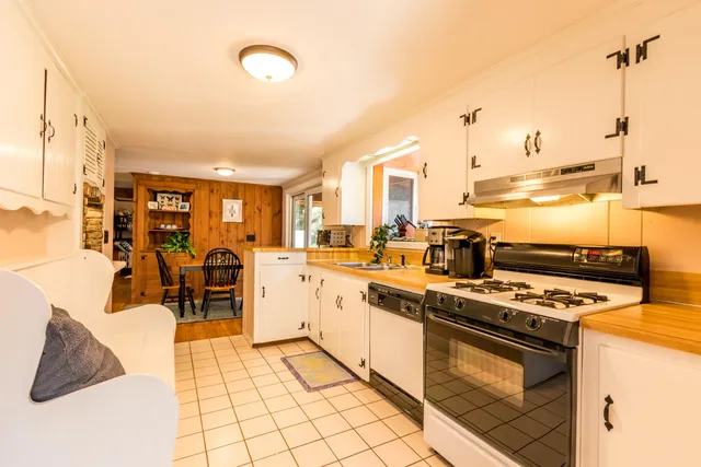 a kitchen with stainless steel appliances granite countertop a stove a sink dishwasher and a refrigerator with wooden floor