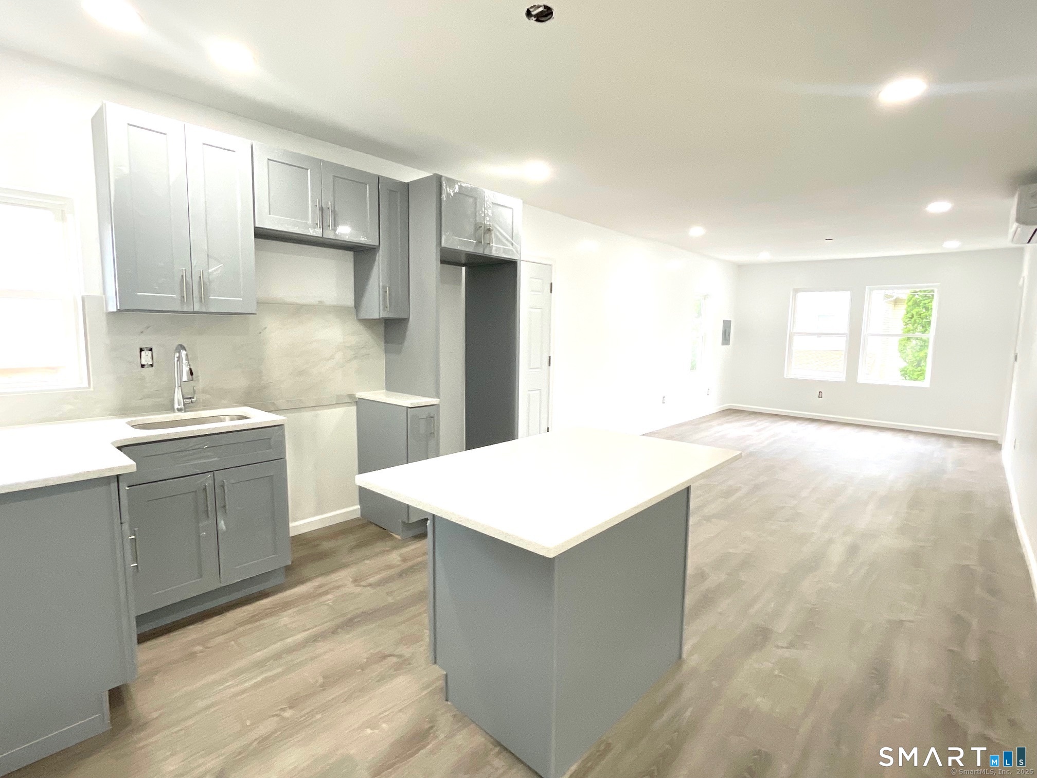 32 Lester Street, Unit 2 Ansonia, CT 06401 - Photo 6 of 9 a large kitchen with stainless steel appliances a large kitchen island a sink dishwasher a stove and white cabinets with wooden floor